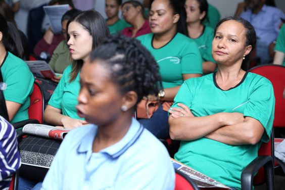 Trabalhadores das escolas ocupam as cadeiras do plenário. Mulher cruza os braços em sinal de reprovação