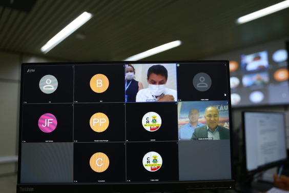 Cinco homens, dois com imagens de rosto e três com imagem da sigla, participam de reunião remota exibida em tela de computador. 