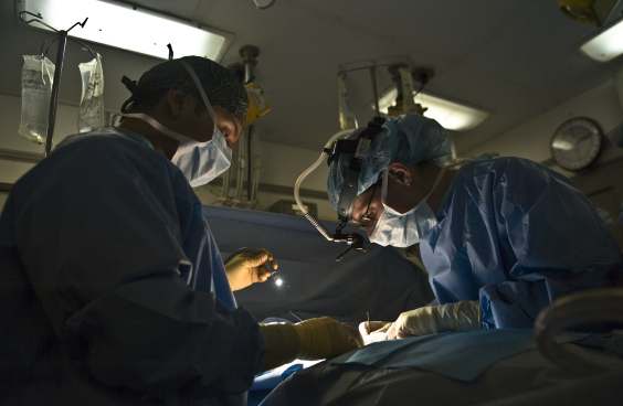 Foto mostra médicos operando paciente 