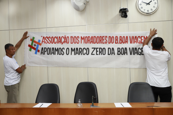 Imagem de faixa fixada na parede do Plenário com os seguintes dizeres: Associação de Moradores apoiam o Marco ZEro na Igreja da Boa Viagem 