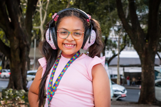 Menina com fone de ouvido e crachá de TEA
