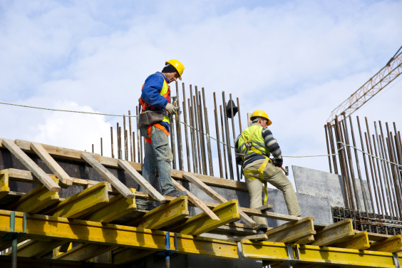 Dois homens vestindo equipamentos de segurança em obra de construção civil