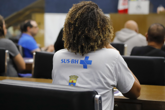 agente de saúde vista de costas acompanhando reunião em plenário da câmara municipal