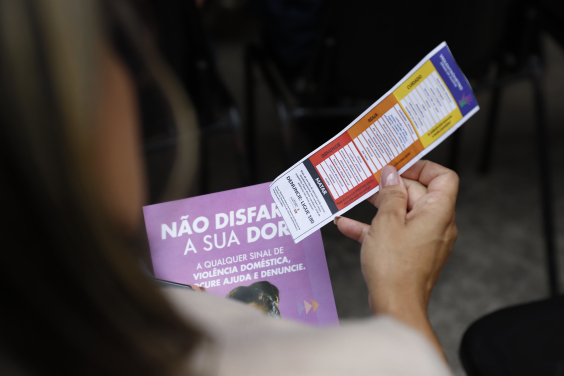 imagem em close de mulher lendo panfleto sobre a campanha agosto lilás
