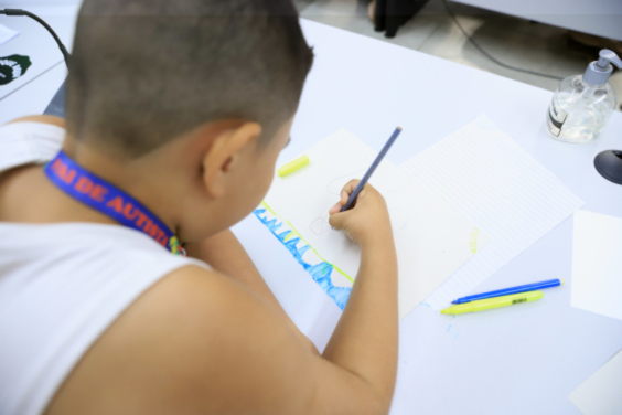 Criança vista de costas escrevendo em caderno com lápis