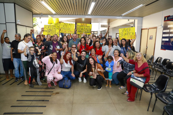 Presentes na audiência pública posam para foto e erguem cartazes