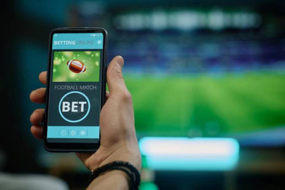 close nas mãos de pessoa segurando um celular com jogo de apostos na tela