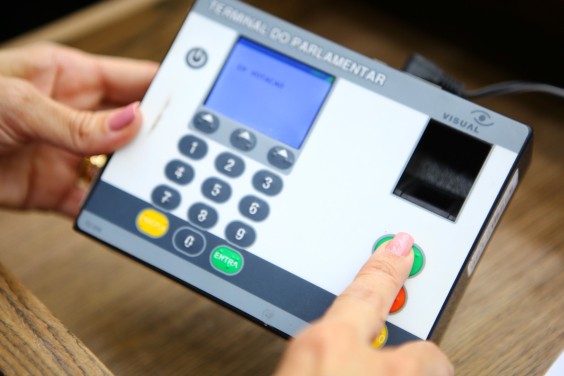 close nas mãos de parlamentar registrando voto em reunião plenária