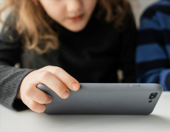 criança olha para um aparelho celular em suas mãos