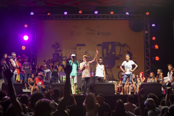jovens se apresentam em palco diante de plateia