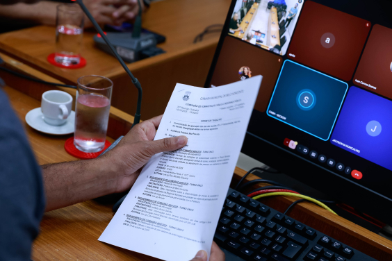 close nas mãos de parlamentar segurando pauta de reunião de comissão