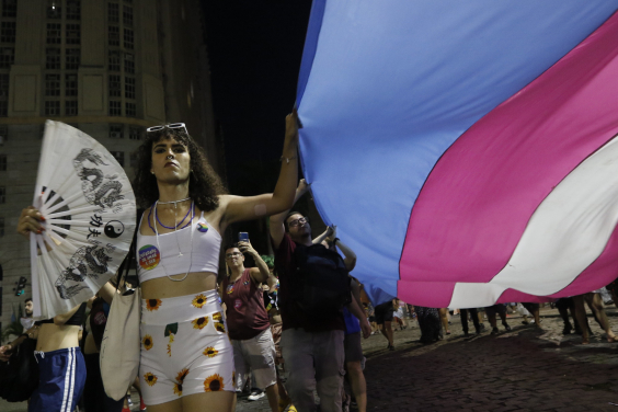 Pessoas levantam bandeira trans