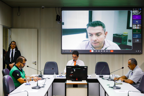 Vereador e convidados da audiência pública reunidos em torno da mesa na CMBH, com um participante online