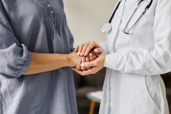 Imagem de médica e paciente segurando as mãos