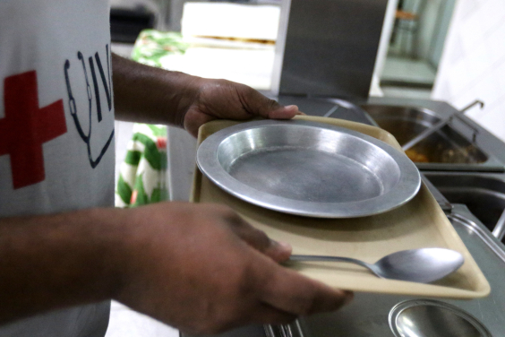 close nas mãos de homem segurando bandeja com prato vazio de comida