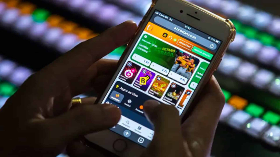 celular nas mãos de pessoa aberto em jogo de apostas