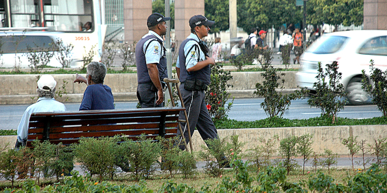 Dois guardas civis municipais caminham em uma praça, durante o dia