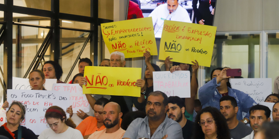 Empreendedores assistem à audiência e erguem cartazes contra o rodízio de food trucks