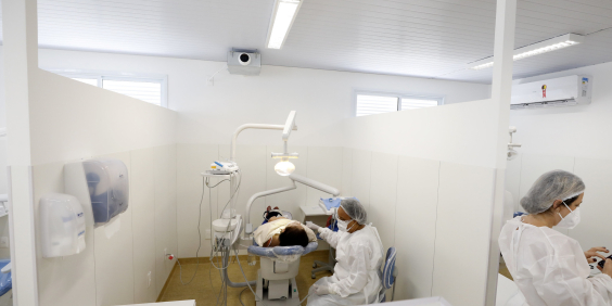 espaço interno de centro de saúde da capital, com profissional realizando atendimento odontológico em paciente