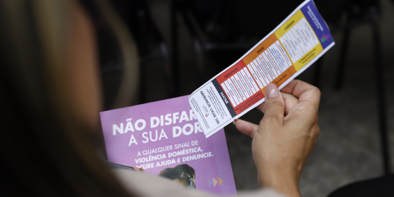 imagem em close de mulher lendo panfleto sobre a campanha agosto lilás
