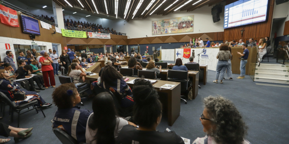 Trabalhadores da saúde sentados no plenário durante audiência pública