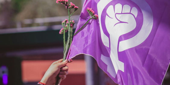 mãos hasteiam bandeira com símbolo do fim da violência contra a mulher