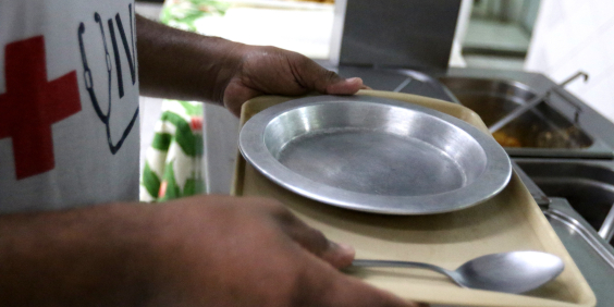 close nas mãos de homem segurando bandeja com prato vazio de comida