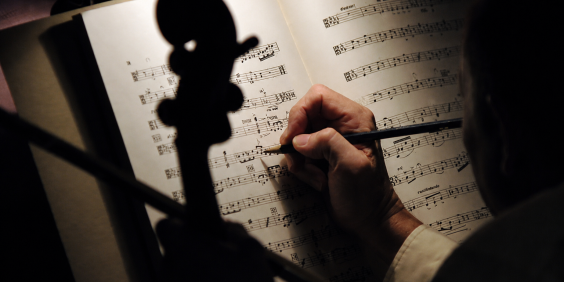 mãos de pessoa fazem anotação em partitura