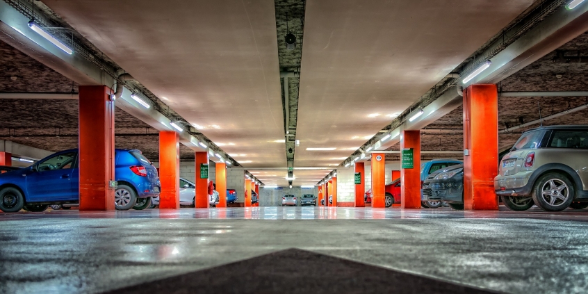 Imagem de estacionamento subterrâneo com veículos parados à esquerda e à direita