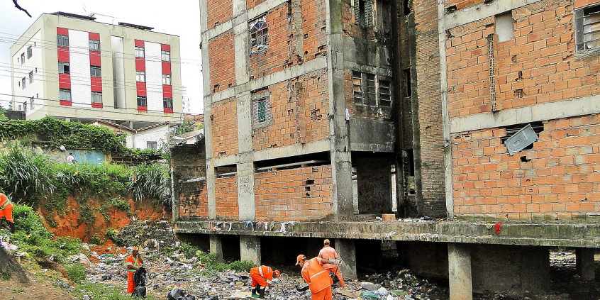 Prédios das torres gêmeas depreciados, em construção não concluída, abandonados. Ao fundo, prédio concluso, pintado em branco