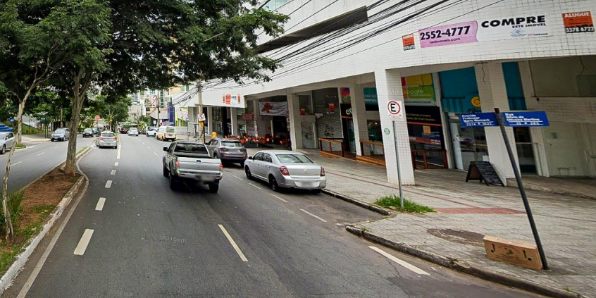 Foto de trecho da Avenida Professor Mário Werneck, com três carros em trânsito e quatro estacionados, durante o dia.