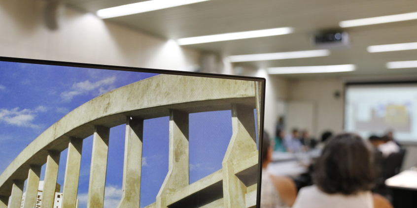 Foto mostra computador com imagem do Viaduto Santa Teresa e pessoas ao fubdo