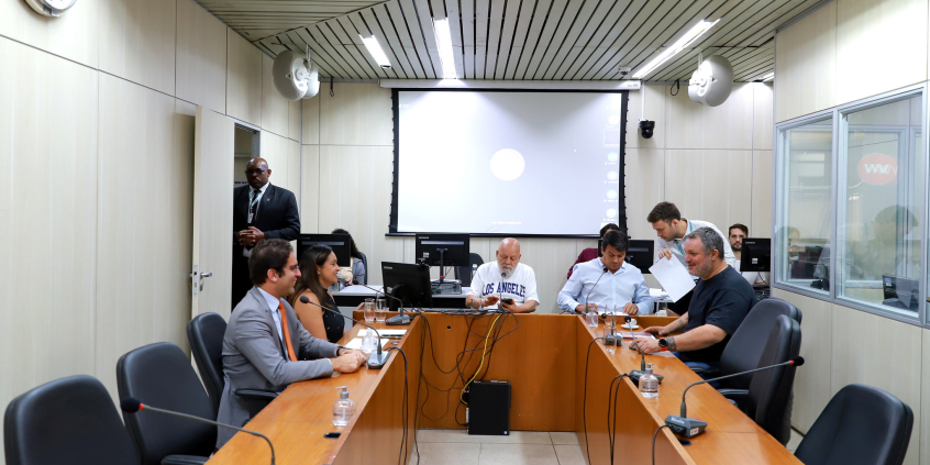 Cinco vereadores reunidos, sentados à mesa, em reunião.