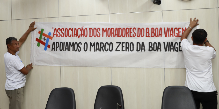 Imagem de faixa fixada na parede do Plenário com os seguintes dizeres: Associação de Moradores apoiam o Marco ZEro na Igreja da Boa Viagem 
