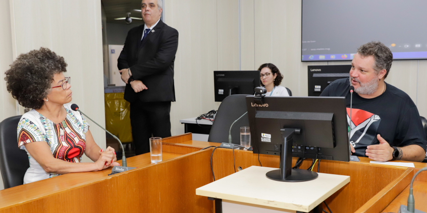 dois vereadores reunidos, sentados à mesa