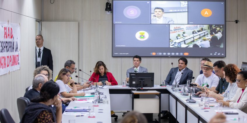 Imagem da mesa de reunião. Na cabeceira, os vereadores dr Célio Frois (PV) e Jorge Santos (Republicanos ) e a deputada estadual Bela Gonçalves (Psol)