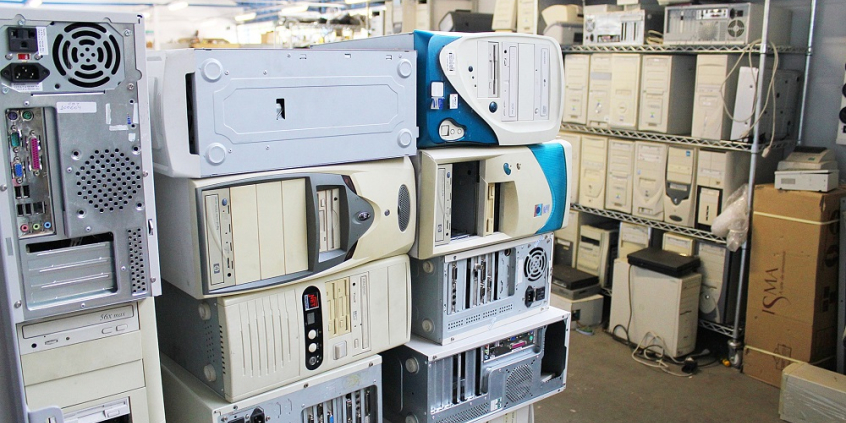 Foto de uma sala cheia de gabinetes de computadores antigos e empilhados.