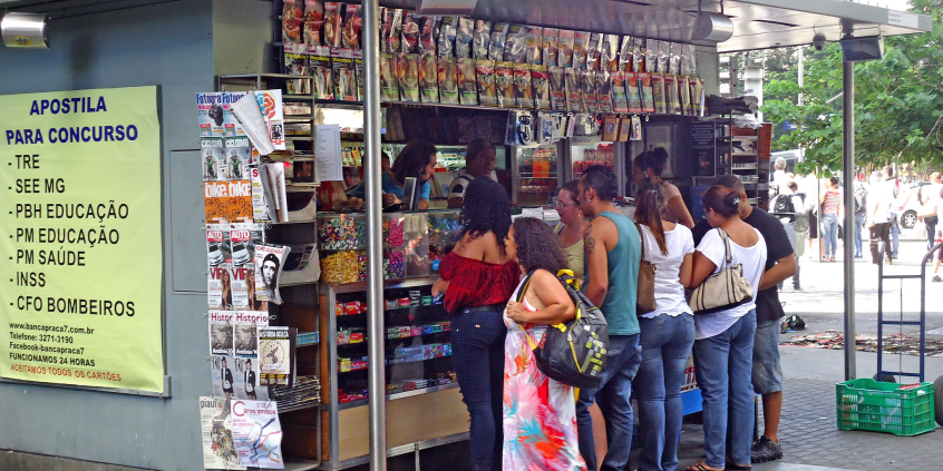 Banca de jornal com clientes aguardando atendimento