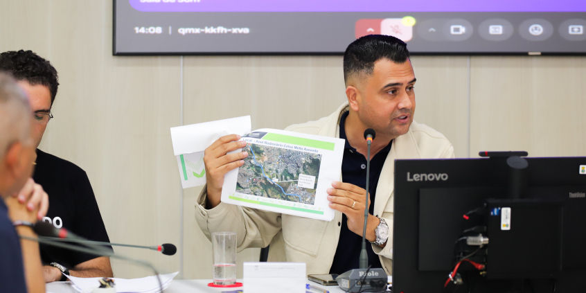 Vereador Irlan Melo segura uma folha com uma foto do Anel Rodoviário.