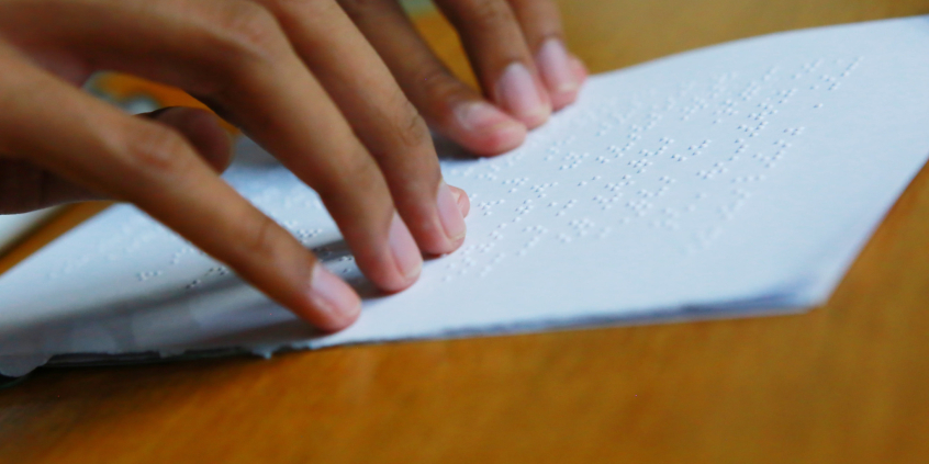 pessoa faz leitura de documento em braille