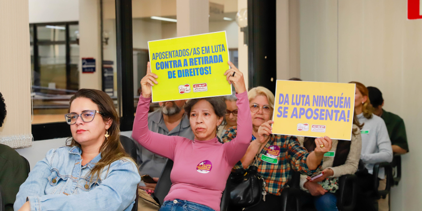 Participantes da audiência mostram cartazes com palavras de ordem