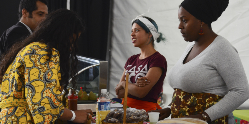 Mulheres atrás de um balcão de salgadinhos atendem clientes