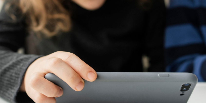 criança olha para um aparelho celular em suas mãos