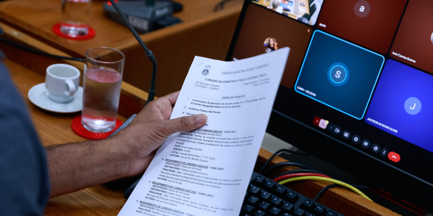 close nas mãos de parlamentar segurando pauta de reunião de comissão
