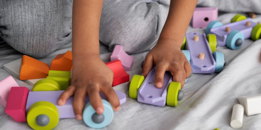 Mãos de crianças brincam com carrinhos de plástico