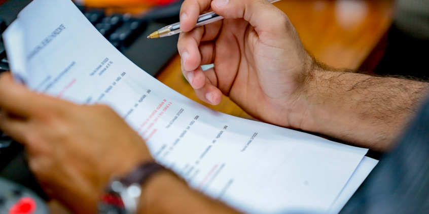 close nas mãos de parlamentar segurando pauta de reunião de comissão