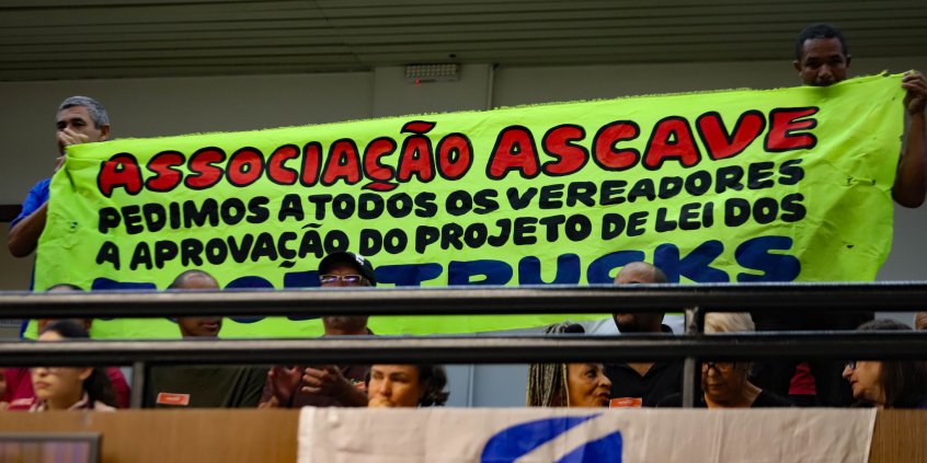 Manifestantes exibem faixa na galeria do plenário com a frase: "Associação Ascave. Pedimos a todos os vereadores a aprovação do projeto de lei dos food trucks"