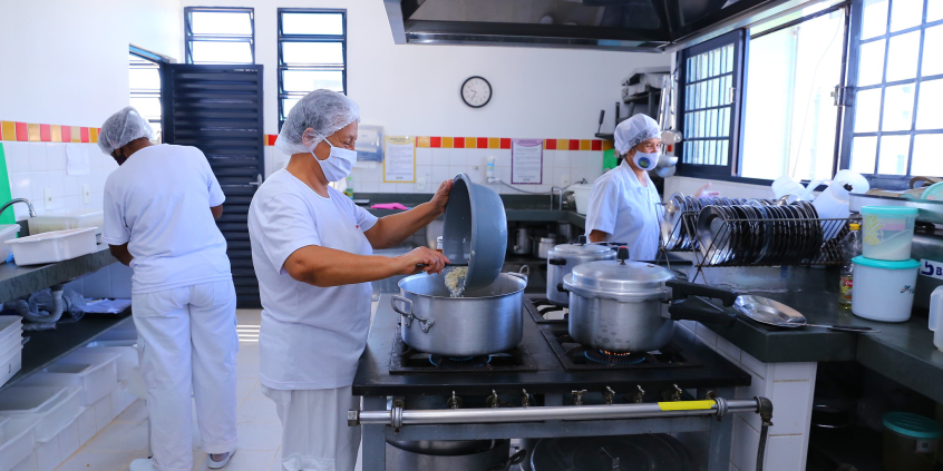 Mulheres preparam merenda em cantina escolar