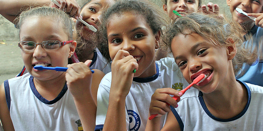 crianças com uniforme de escola seguram escova de dentes
