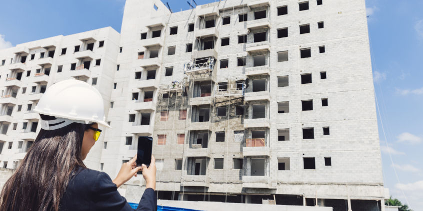 mulher com capacete fotografa prédio em construção